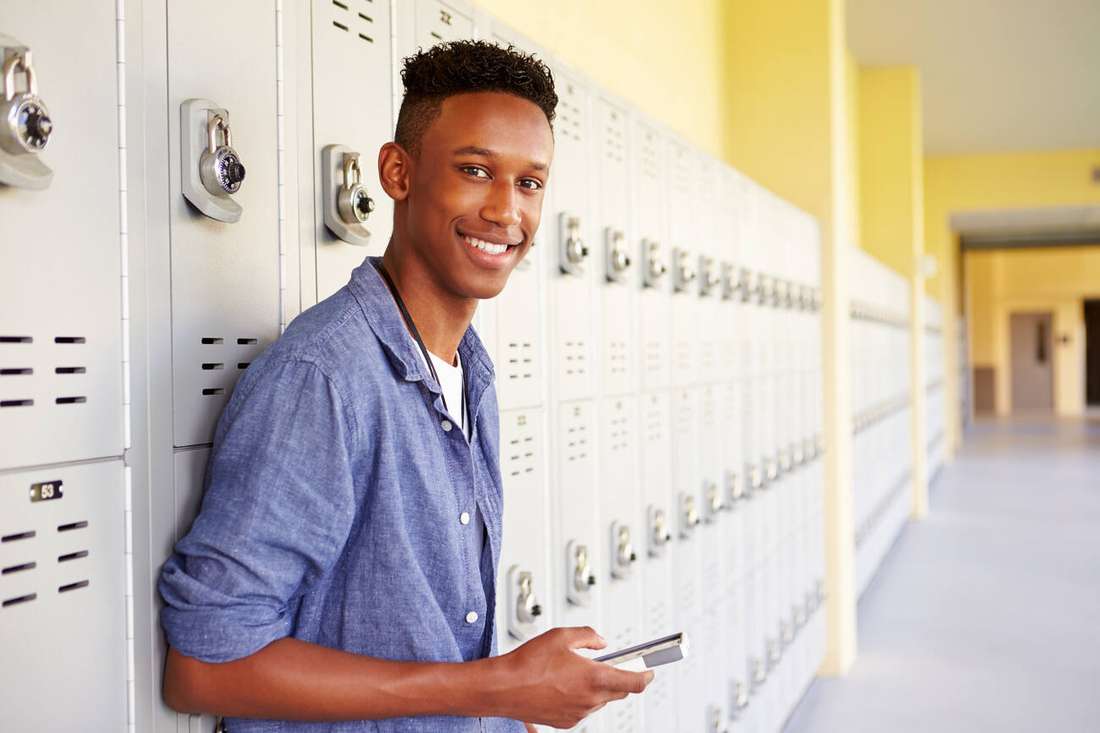 A smiling young man leaning against a row of lockers