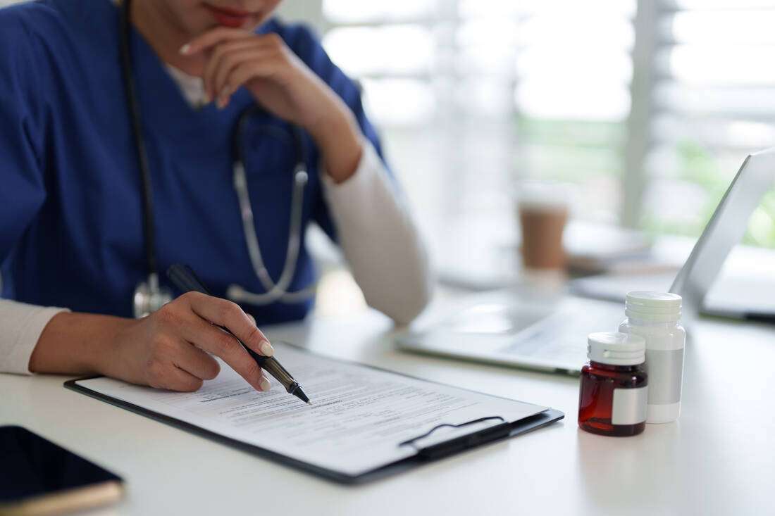 A healthcare worker writing notes on a clipboard