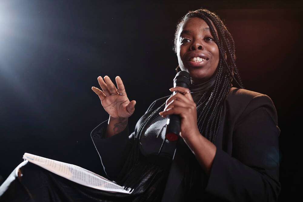 A woman speaking passionately into a microphone on stage