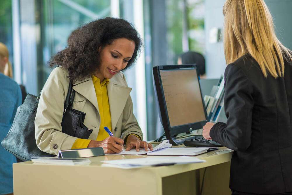 A woman completing paperwork with help from a staff member