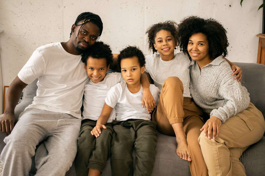 A smiling family of five sitting close together on a couch