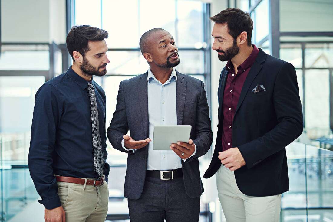 Three professional men talking together in a modern office